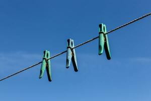 Tres pinzas para la ropa colgando en un tendedero con azul cielo foto