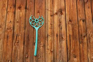 broken plastic carpet beater hanging on a nail on a wooden wall photo