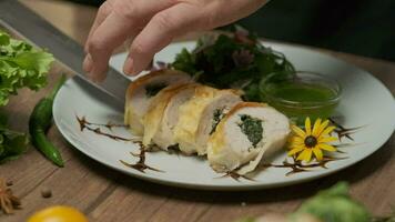 Serving chicken roll with spinach. There are greens and green oil on the plate. Close-up with hands, slow motion. video