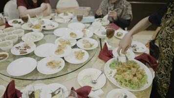 4k 25fps video footage. Restaurant waiter serves crispy fried chicken with lettuce on a round glass table for customers. Selective focus.