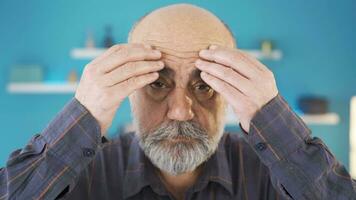 The old man looking at his wrinkled features is unhappy and sad. video