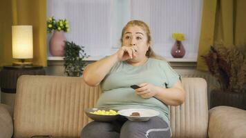 Fettleibigkeit Frau isst Snacks während Aufpassen Fernseher. video