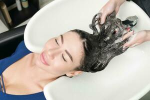 Professional hairdresser working with brunette woman photo