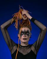 Informal young female with colored braids hairdo and spooky black stage makeup painted on face photo