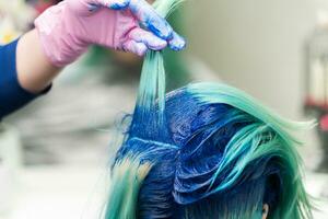 Hairdressers raise shock of blue hair of client during coloring process photo