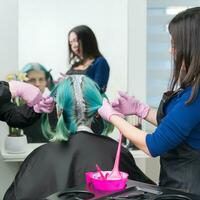 proceso de pelo colorante en belleza salón. dos Maestro peluquería aplicar pintar a pelo durante blanqueamiento pelo raíces foto