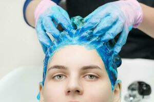 Hairstylist hands in gloves washing hair with shampoo and conditioner in professional beauty salon photo