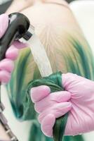 Professional hairdresser washes long green hair of client in sink with water from shower photo