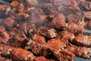 Barbecue cooking on skewers on charcoal grill with smoke. Close-up view photo