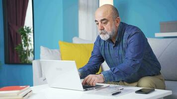 velho homem tendo dificuldade usando computador portátil. video