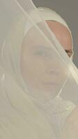 ein Frau im Weiß Hijab ist halten ein Weiß Schleier video