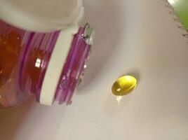 Fish oil capsule out of the bottle photo