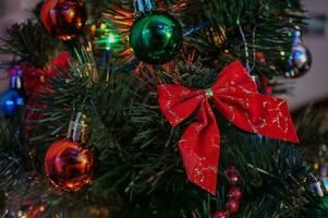 nuevo años juguetes en el Navidad árbol. Navidad árbol decoraciones de cerca. guirnaldas, rojo y verde globos, arcos en un verde pino árbol. Navidad atmósfera a hogar, antecedentes para fiesta tarjetas foto