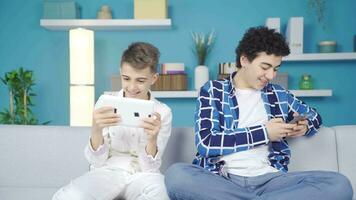 twee vrienden spelen spellen met telefoon en tablet. video