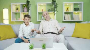 Old man and boy looking at laptop with confused expression. video