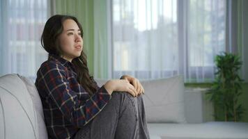 depressivo e preocupado ásia mulher sentado sozinho em sofá às lar. video
