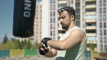 Boxer hombre envuelve vendajes en su manos. video