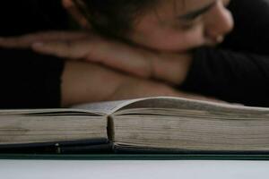 Tired young woman lying on a book after hard work. photo