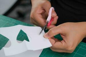 un mujer cortes fuera un blanco en forma de corazon papel con tijeras a Decorar. San Valentín día saludo tarjeta o fiesta regalo concepto. foto