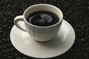 Black coffee in white cup isolated on background of roasted coffee beans. photo