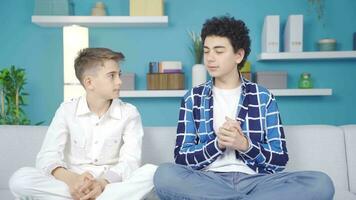 Two praying brothers looking at each other at home and smiling. video