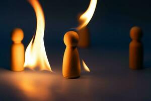 The wooden figure, isolated from the crowd with a fire, being chased away due to confusion and conflict with others. Concepts of dissent, rejection, doubt, anger and revenge. photo