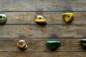 Wooden wall playground with rock climbing simulator design at outdoor playground in park. Wooden planks playground with colorful stone cliff climbing model in the public garden. photo