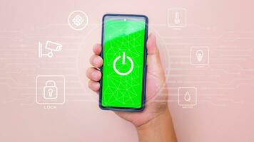 Male hand holding smart phone on pink background with smart home technology interface on smartphone app screen. Concept of automation. photo