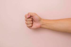 Male hand with fist gesture isolated on pink background. Male clenched fist. photo