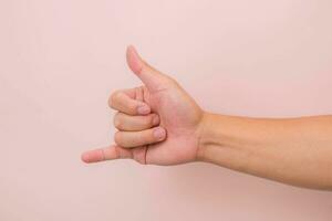 Call me hand sign or gesture isolated on pink background. photo