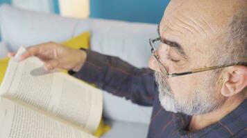 velho homem com óculos lendo uma livro. video