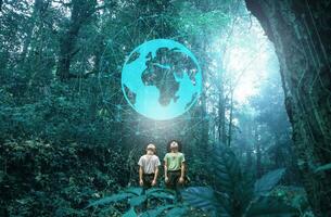 Two siblings were excited to look up at the world icon on the beautiful rainforest background. Family on a hiking adventure through the forest. Technology and imagination concepts photo