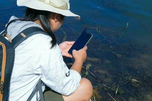 hembra ambientalista utilizando móvil teléfono a grabar análisis de patógenos en natural aguas agua y ecología concepto foto