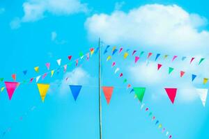 Colorful small flags in the sky. Waving small colorful flags hanging on the rope for holidays against blue sky. photo
