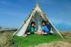 Cute little sisters playing in a small tent in the backyard. Adorable child playing and looking out from the wigwam. photo