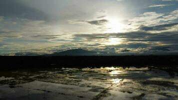 aéreo ver de el inundado agrícola campos en contra el antecedentes de el oscuridad de el montañas y el nublado cielo a oscuridad. hermosa naturaleza de tormenta nubes en el tiempo de día. foto