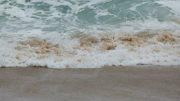 View of ocean waves and sand on the beach of tropical seas in Thailand. Strong sea waves crash to shore in the rainy season. photo