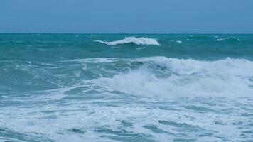 View of sea waves on the beach of tropical seas in Thailand. Strong sea waves crash to shore in the rainy season. Beautiful sea waves with foam of blue and turquoise color. photo