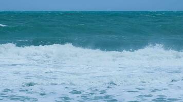 View of sea waves on the beach of tropical seas in Thailand. Strong sea waves crash to shore in the rainy season. Beautiful sea waves with foam of blue and turquoise color. photo