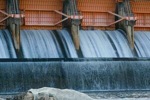 Hydroelectric dam, floodgate with flowing water through gate and open springway at Kew Lom Dam, Lampang, Thailand. Dam photo