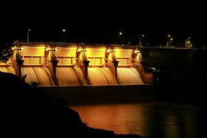 Evening scenery at Kiew Lom Dam, Lampang, Thailand. Hydroelectric dam, floodgate with water flowing through the gate with beautiful lights. Dam with hydroelectric power plant and irrigation. photo