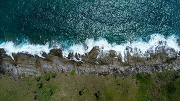 vista aérea de las olas del mar rompiendo en el acantilado de rocas en el océano azul. vista superior de las rocas costeras en el océano de phuket. punto de vista del paisaje del cabo laem phromthep por la mañana. foto