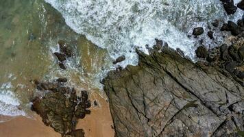 Aerial view of sea waves crashing on rocks cliff in the blue ocean. Top view of coastal rocks in Phuket ocean. Landscape view point of Laem Phromthep Cape in the morning. photo