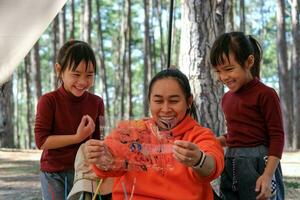 Happy loving family. Two little girls painted their mother's face with watercolors. Mother's day. Happy mother and child spend winter holidays together in a pine forest. photo