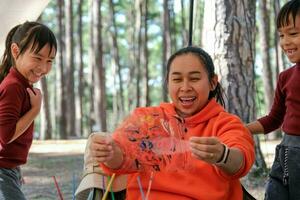 Happy loving family. Two little girls painted their mother's face with watercolors. Mother's day. Happy mother and child spend winter holidays together in a pine forest. photo