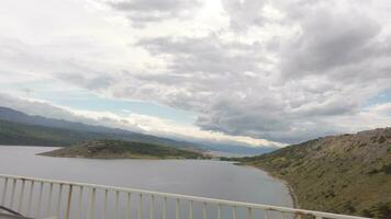 une vue de une pont plus de une Lac avec montagnes dans le Contexte video