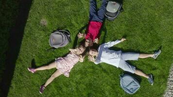 three people laying on the grass with backpacks video