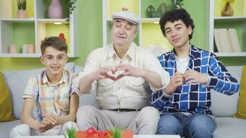 abuelo y nietos mirando a cámara y haciendo corazones. video