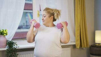 obesità donna Lavorando su pesi con manubri nel davanti di il bicchiere. video