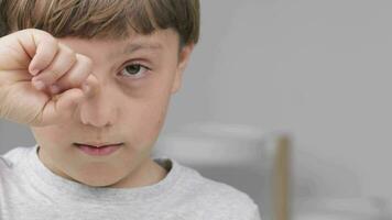 a young boy is holding his hand to his eye video